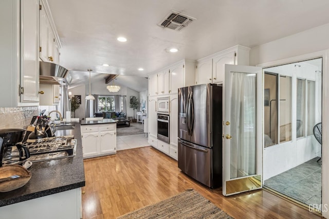 kitchen featuring white cabinets, vaulted ceiling, decorative light fixtures, kitchen peninsula, and stainless steel appliances