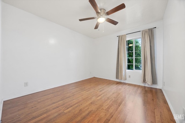 spare room featuring ceiling fan, light wood finished floors, and baseboards