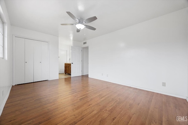 unfurnished bedroom featuring ceiling fan, a closet, wood finished floors, and baseboards