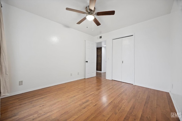 unfurnished bedroom featuring a closet, visible vents, a ceiling fan, wood finished floors, and baseboards