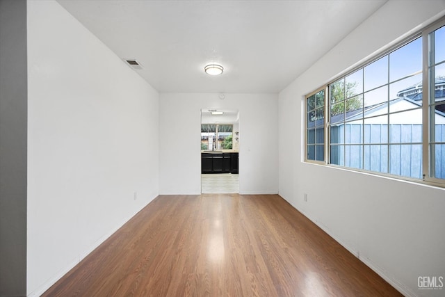 unfurnished room with a sink, baseboards, visible vents, and wood finished floors