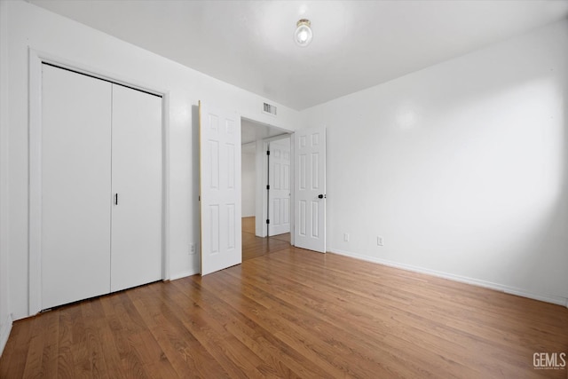 unfurnished bedroom with baseboards, light wood-style flooring, visible vents, and a closet