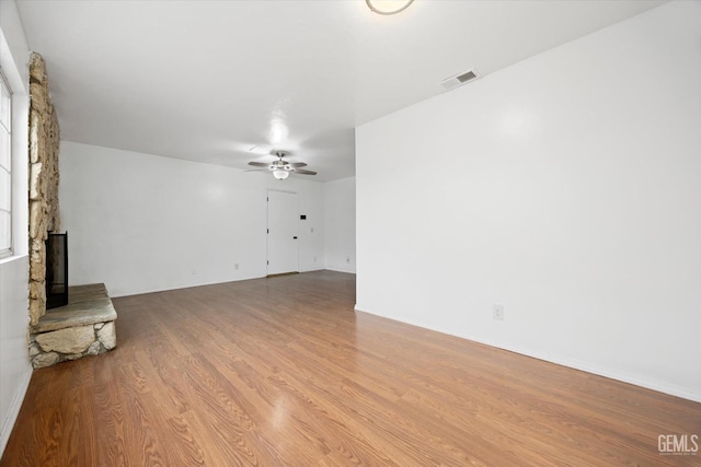 unfurnished living room with light wood-type flooring, a fireplace, visible vents, and a ceiling fan