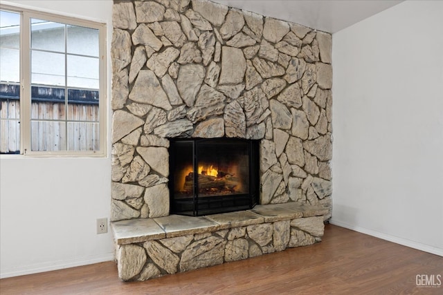 details with a stone fireplace, baseboards, and wood finished floors