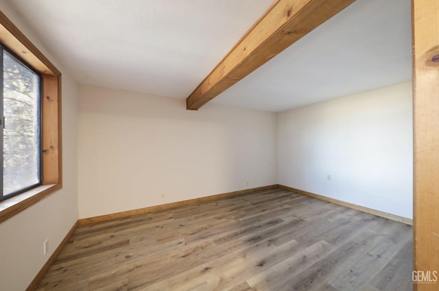 spare room with beam ceiling and wood-type flooring