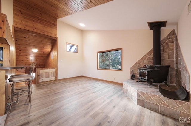 living room with a wood stove, wood ceiling, lofted ceiling, and light hardwood / wood-style floors