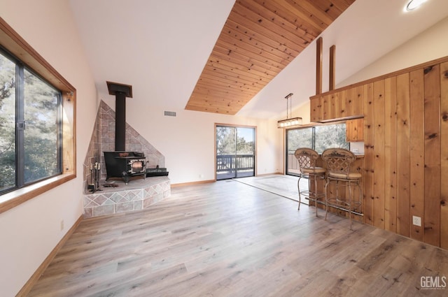 unfurnished living room with high vaulted ceiling, light hardwood / wood-style floors, a wood stove, and wood ceiling