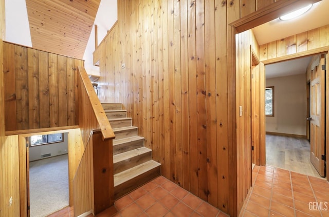 staircase with tile patterned floors and wooden walls