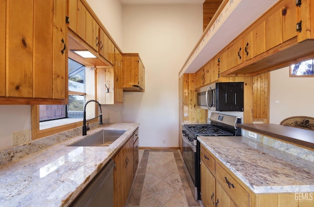 kitchen featuring light stone countertops, appliances with stainless steel finishes, light tile patterned flooring, and sink