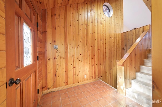 entryway with wood walls, light tile patterned floors, and wooden ceiling