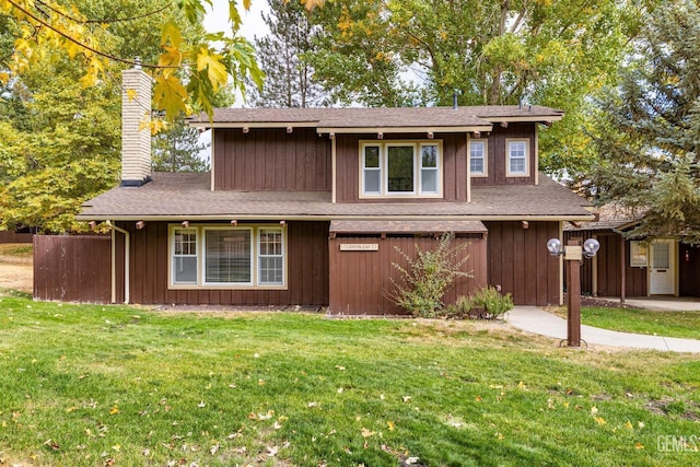 traditional-style home featuring fence, a front yard, a chimney, and a shingled roof