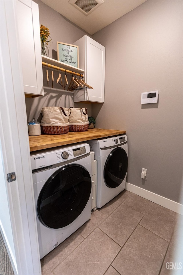 washroom featuring light tile patterned floors, washing machine and dryer, and cabinets