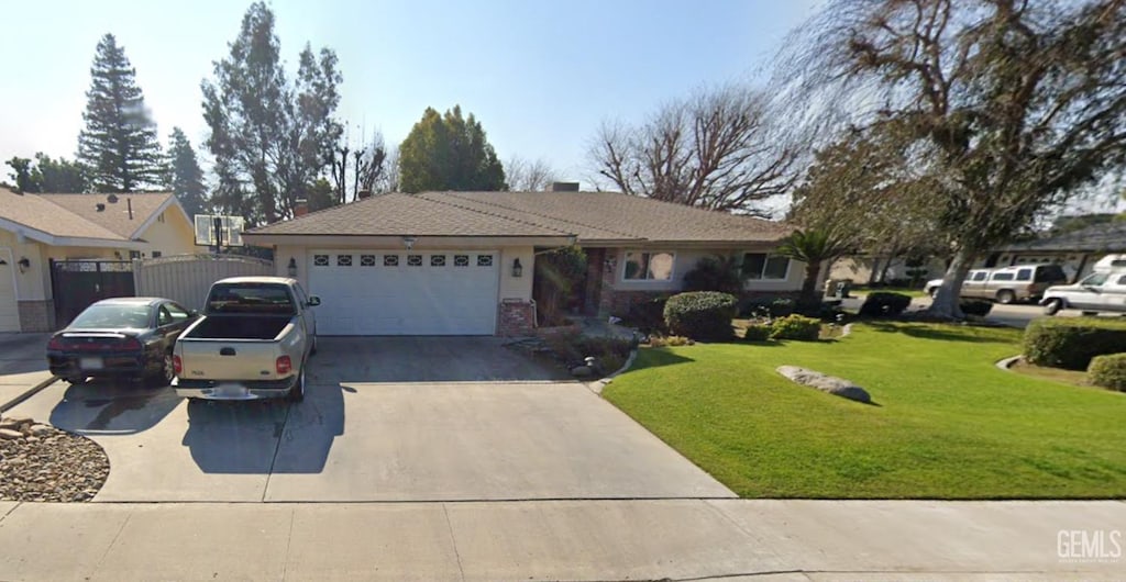 ranch-style house featuring a garage and a front lawn