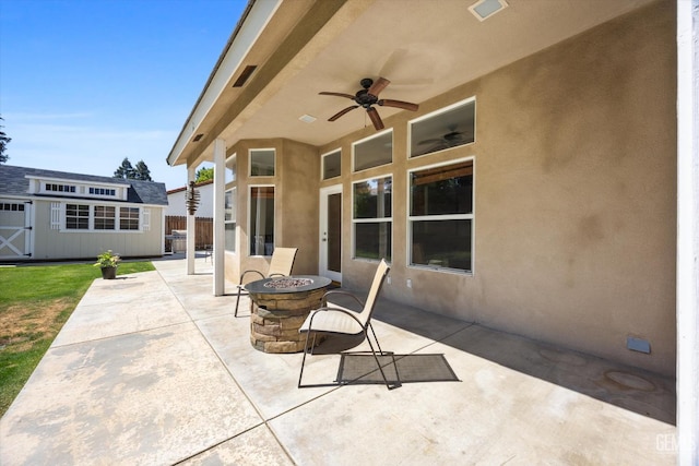 view of patio / terrace featuring a ceiling fan, visible vents, an outbuilding, fence, and a fire pit