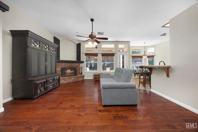 living room with a ceiling fan, baseboards, visible vents, and dark wood-style floors