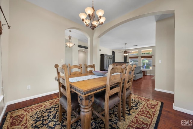 dining room with arched walkways, baseboards, ceiling fan with notable chandelier, and wood finished floors
