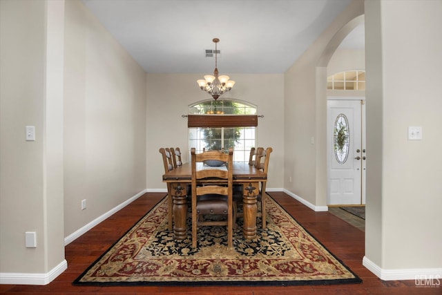 dining area featuring a notable chandelier, arched walkways, baseboards, dark wood-type flooring, and visible vents