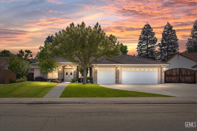 view of front facade featuring fence, an attached garage, stone siding, concrete driveway, and a yard
