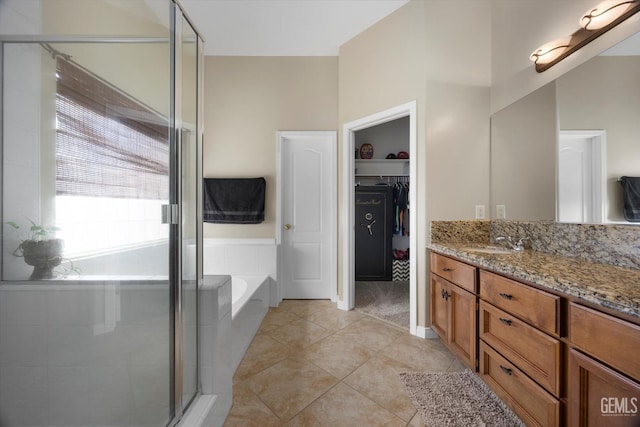 bathroom featuring tile patterned flooring, vanity, a spacious closet, a bath, and a stall shower