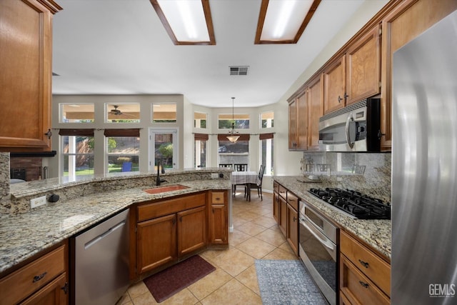 kitchen with visible vents, brown cabinetry, decorative backsplash, a sink, and stainless steel appliances
