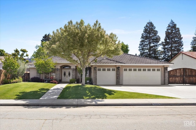 view of front of house with fence, stone siding, a garage, a front yard, and driveway