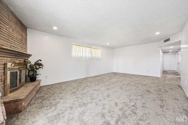 unfurnished living room with carpet, a fireplace, visible vents, and a textured ceiling