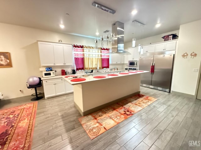 5917 Hawthorn Tree Ln, Bakersfield, CA 93313 - kitchen with appliances with stainless steel finishes, island exhaust hood, light wood-style flooring, a kitchen island, and white cabinets