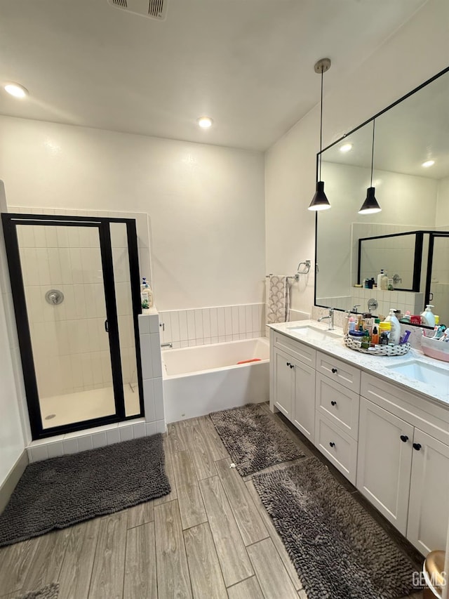5917 Hawthorn Tree Ln, Bakersfield, CA 93313 - bathroom featuring a garden tub, double vanity, wood finished floors, a shower stall, and recessed lighting