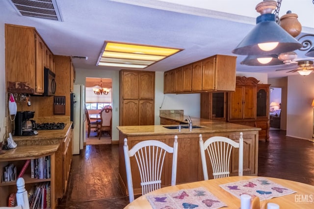 kitchen with sink, dark wood-type flooring, white refrigerator, kitchen peninsula, and ceiling fan with notable chandelier