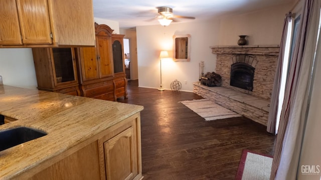 living room featuring dark hardwood / wood-style floors, ceiling fan, sink, and a fireplace