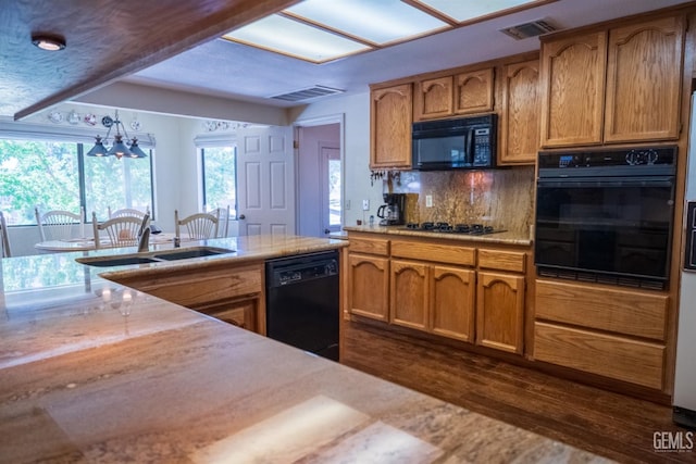 kitchen featuring sink, dark hardwood / wood-style flooring, a notable chandelier, decorative backsplash, and black appliances