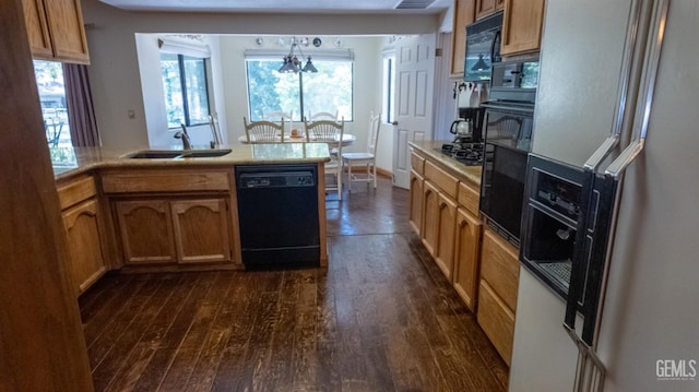 kitchen with dark wood-type flooring, sink, black appliances, and a notable chandelier