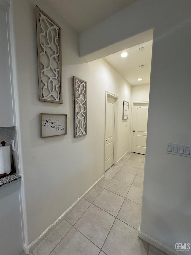 hallway with recessed lighting, baseboards, and light tile patterned flooring