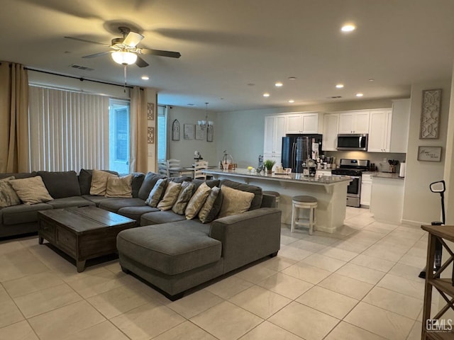 living room featuring light tile patterned floors, ceiling fan with notable chandelier, visible vents, and recessed lighting