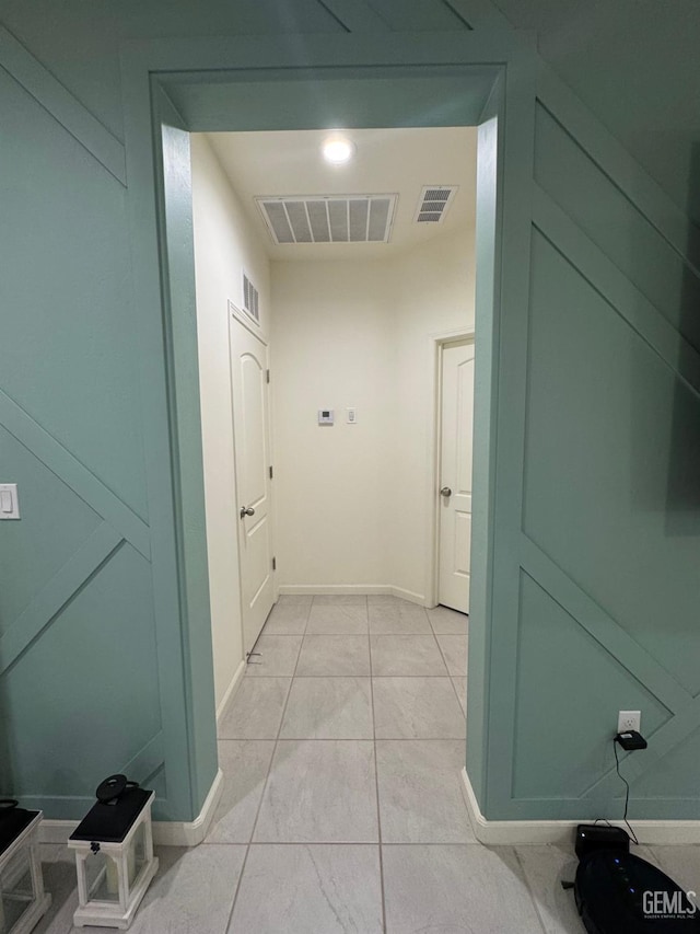 hall featuring light tile patterned floors, visible vents, and baseboards