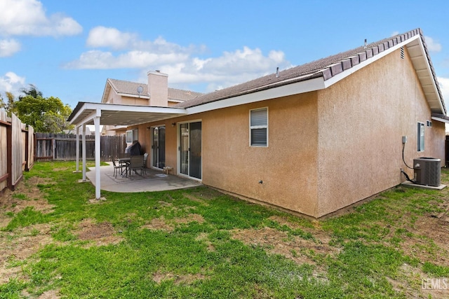 rear view of property featuring central air condition unit, stucco siding, a lawn, a fenced backyard, and a patio