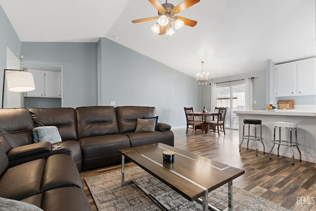 living room featuring ceiling fan with notable chandelier, baseboards, dark wood-type flooring, and lofted ceiling