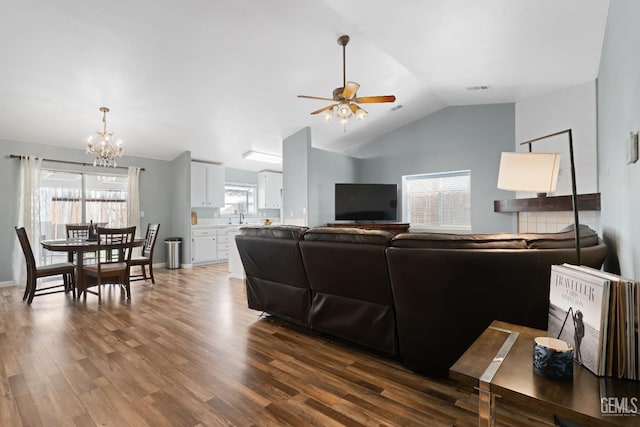 living room featuring a wealth of natural light, visible vents, ceiling fan with notable chandelier, and dark wood-style flooring