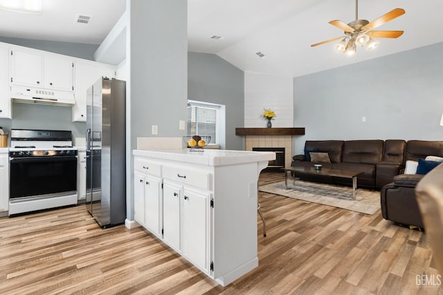 kitchen with visible vents, stainless steel fridge with ice dispenser, under cabinet range hood, range with gas stovetop, and a peninsula