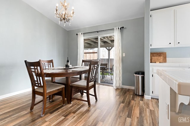 dining space featuring baseboards, a notable chandelier, and wood finished floors