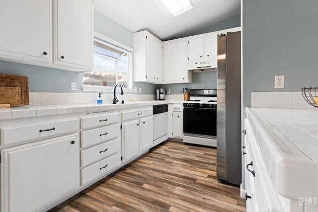 kitchen with under cabinet range hood, freestanding refrigerator, gas stove, white dishwasher, and vaulted ceiling