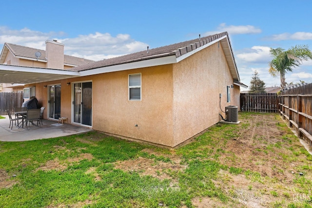 rear view of property with stucco siding, a patio, a fenced backyard, a yard, and central AC unit