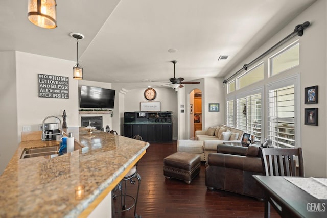 living room featuring ceiling fan, sink, and dark hardwood / wood-style flooring