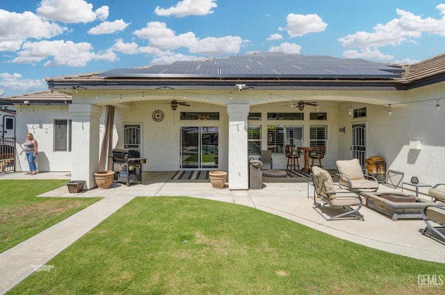 back of house featuring a lawn, a patio area, ceiling fan, and solar panels