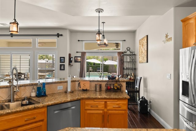 kitchen featuring pendant lighting, appliances with stainless steel finishes, sink, and dark stone countertops