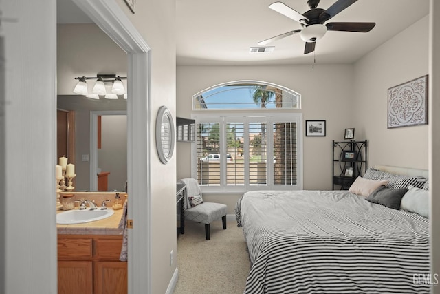 carpeted bedroom featuring sink, ensuite bath, and ceiling fan