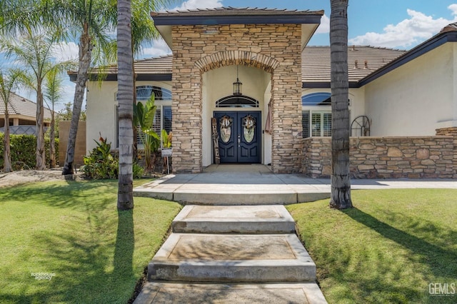 view of exterior entry featuring a yard and french doors