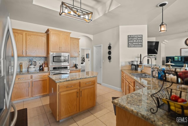 kitchen featuring pendant lighting, a kitchen island, stone countertops, and appliances with stainless steel finishes