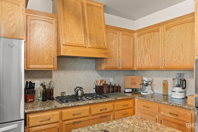 kitchen featuring stainless steel appliances, light stone countertops, and backsplash