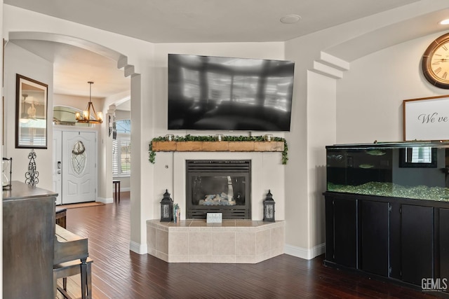 living room with an inviting chandelier, a fireplace, and dark hardwood / wood-style flooring